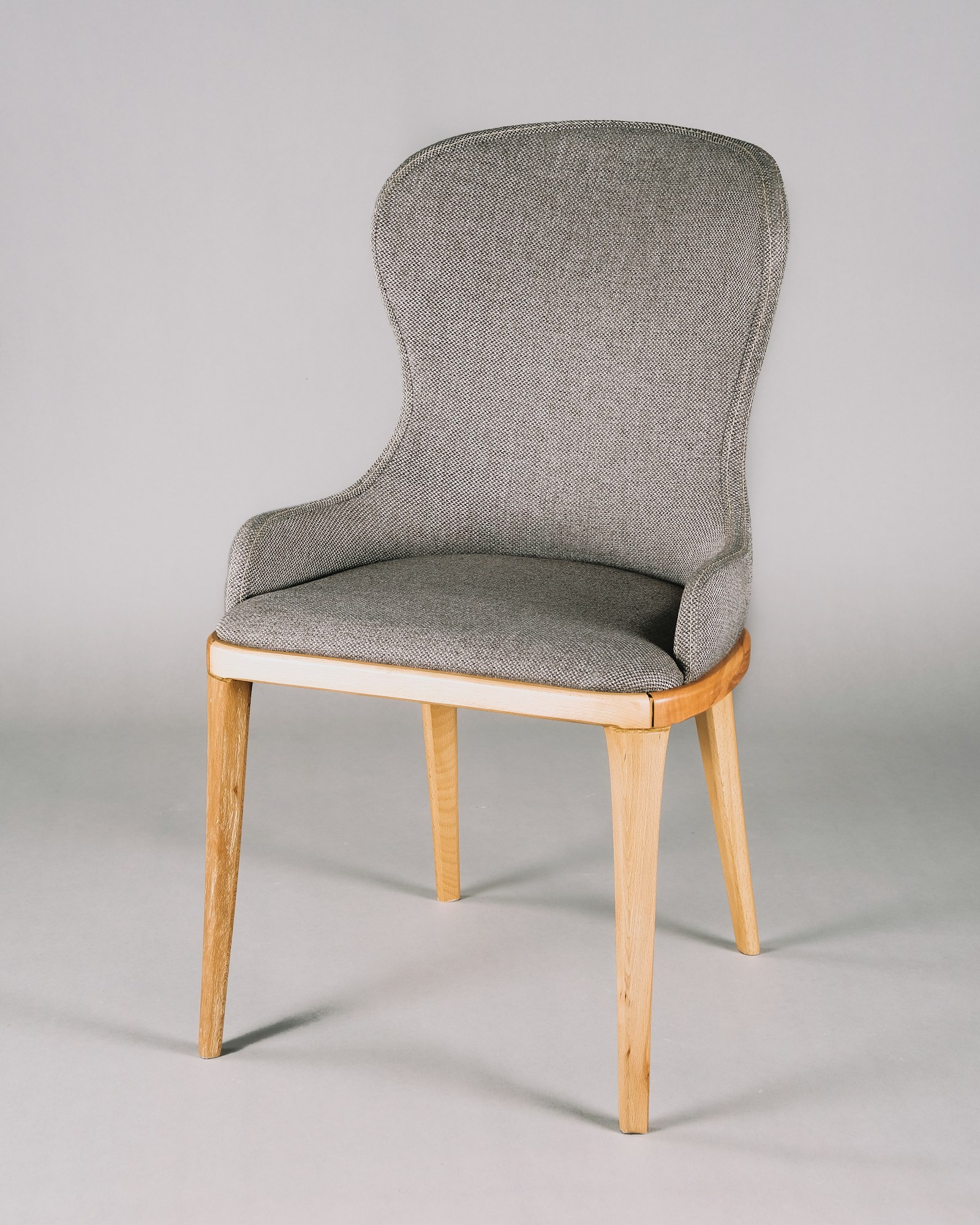 A sculptural upholstered chair with natural wood detailing
